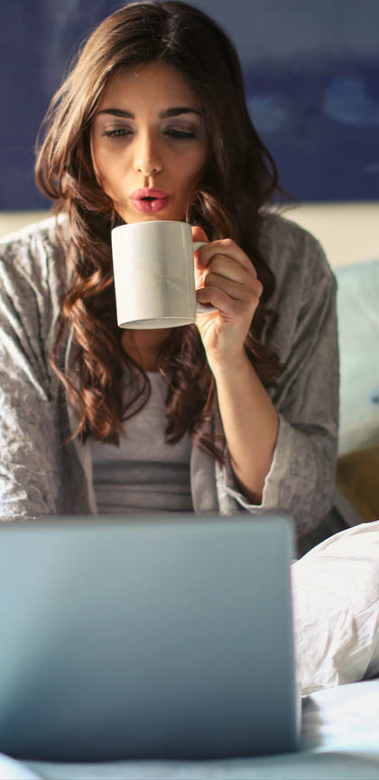 Woman working on her laptop and drinking coffee at home  